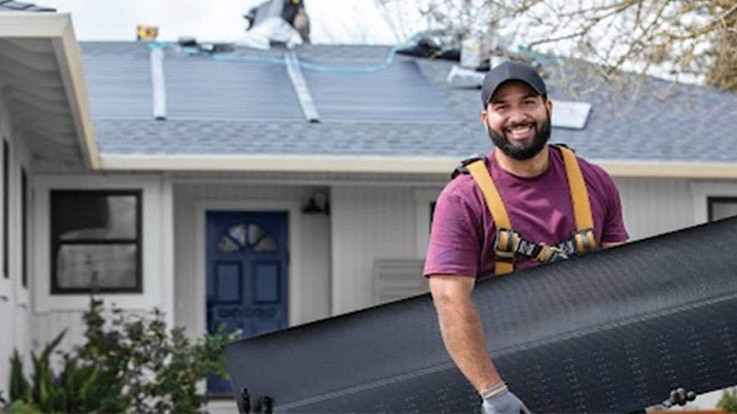 168极速赛车开奖官方开奖 Solar roofing contractor in front of home holding solar roof shingles