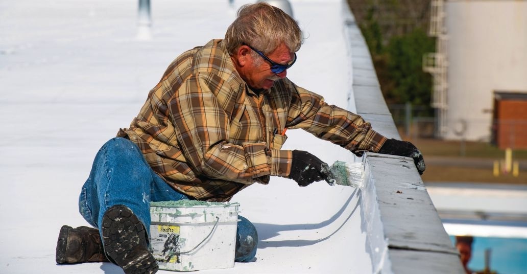 Application of acrylic topcoat at parapet wall detail. (Editor's note: There is a lower roof adjacent to the parapet that is not visible in this photo.)