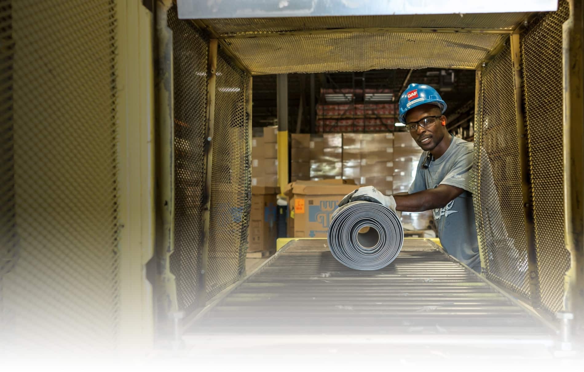 GAF employee with roll of roofing material