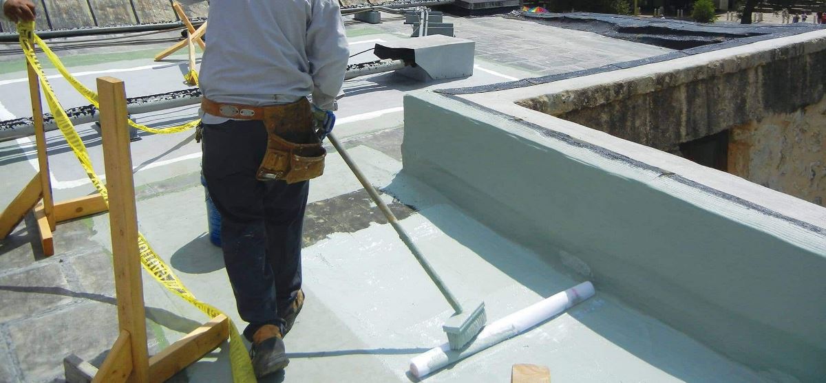 Commercial contractor applying GAF coating on a flat roof at the Alamo