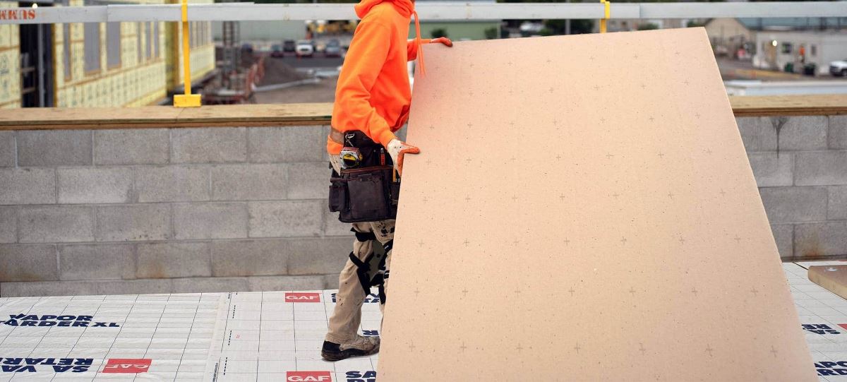 Contractor with panel of GAF EnergyGuard Tapered Polyiso Insulation on Bozeman roof. 