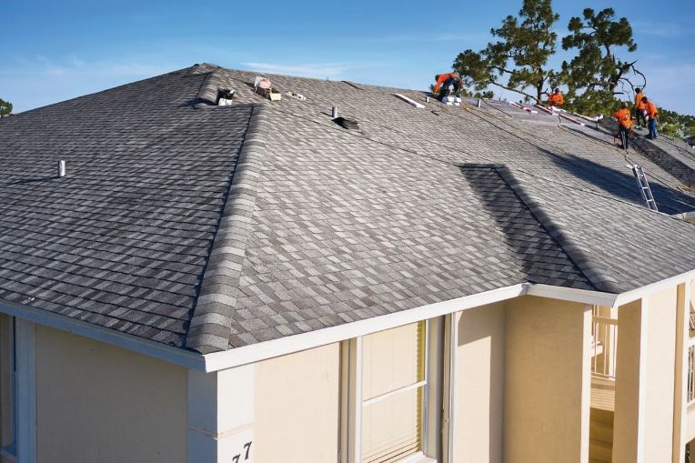 Roofing team installing new gray roof on stucco home