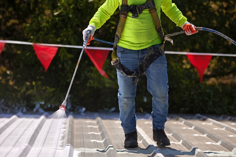 Roofing contractor coating roof with HydroStop