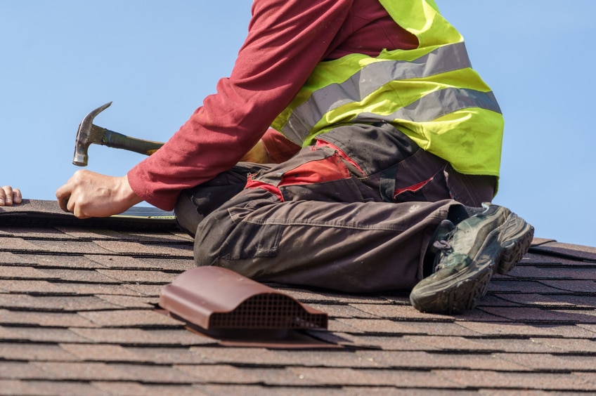 Concept of construction process. Two skilled roofer in special work wear with helmet in hands instal