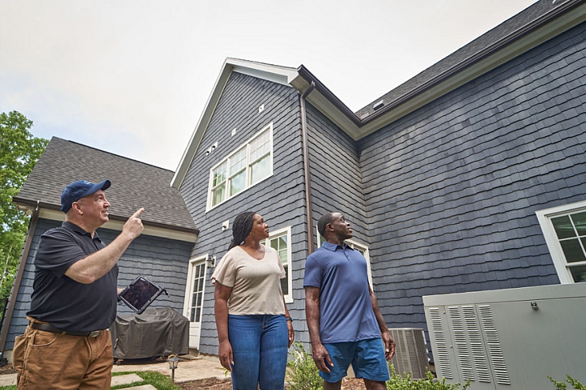 A couple looks at their home from the ground.