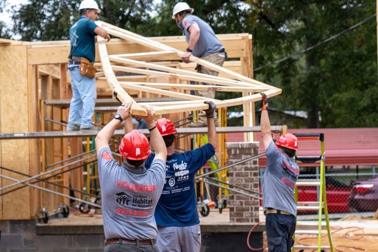 GAF employees volunteering and lifting wood at Habitat for Humanity site in their community