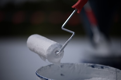 Roller brush rolling a coating on a roof