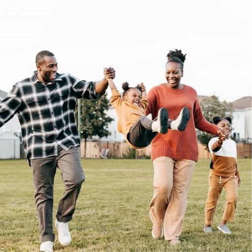 Happy family with man and women swinging child in air