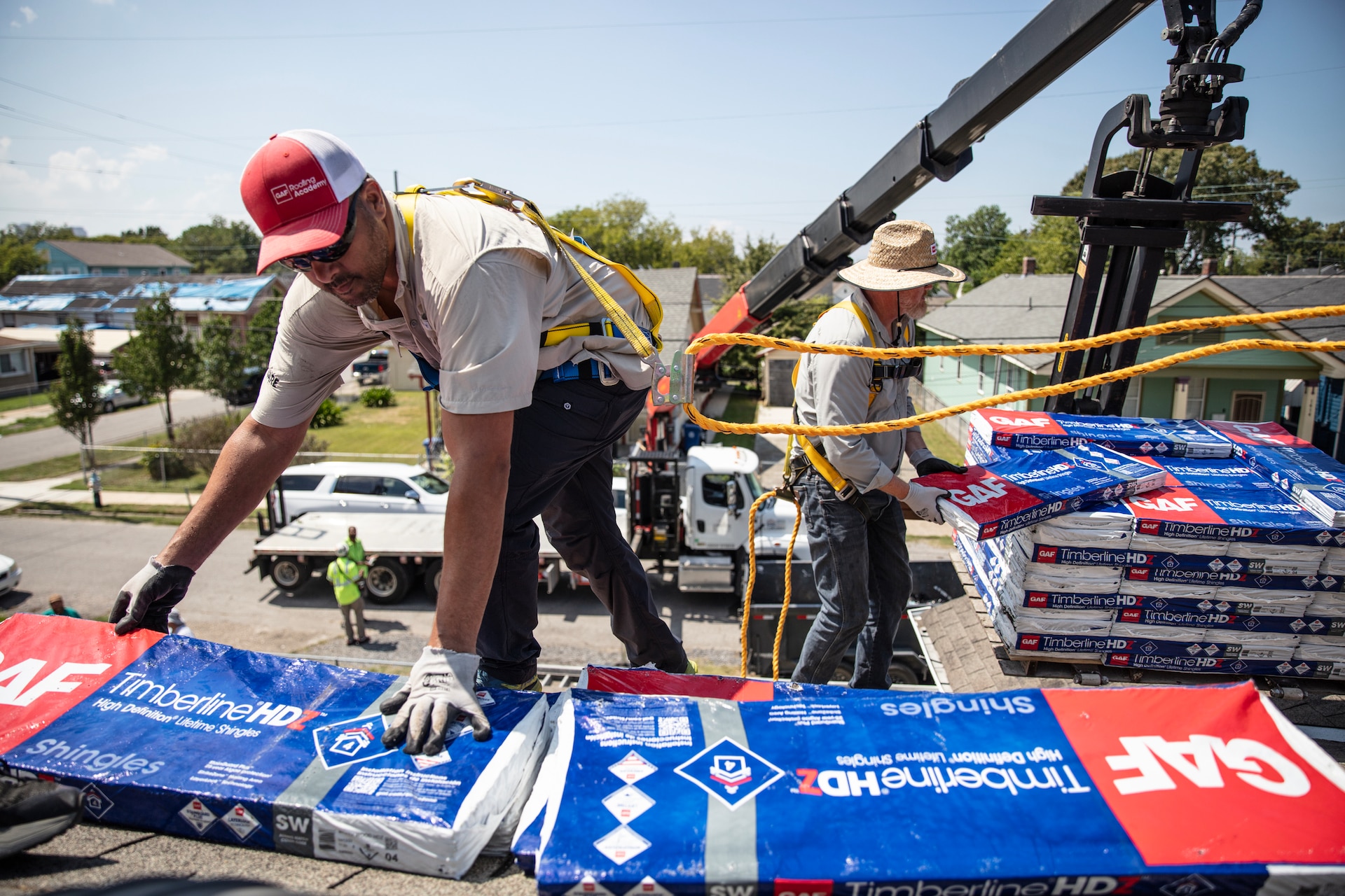 GAF Roofing Academy Instructor Gary Pierson grabs a pack of GAF roofing shingles while on a house.