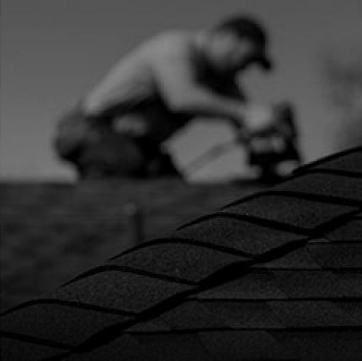 Shaded image of a GAF roofer installing GAF hip and ridge cap shingles to a residential roof