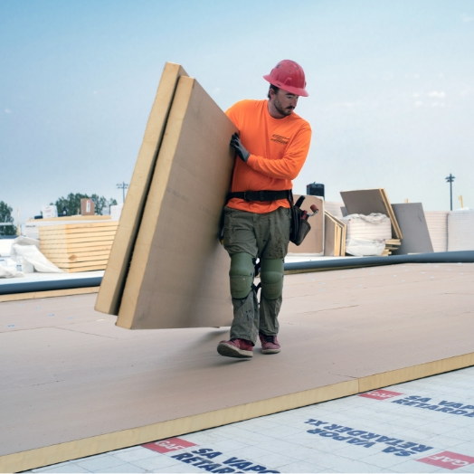 GAF contractor carrying insulation panels on a commercial roof job site