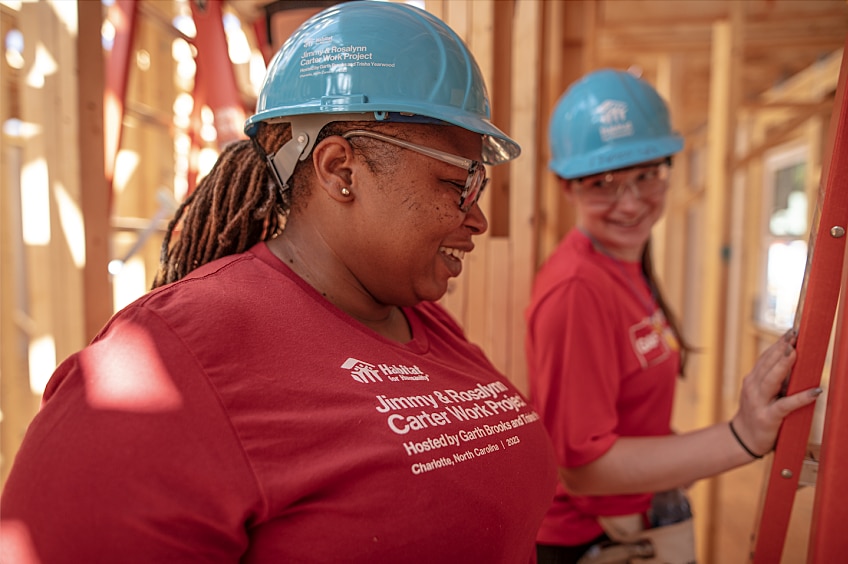 Two women work together to build a house