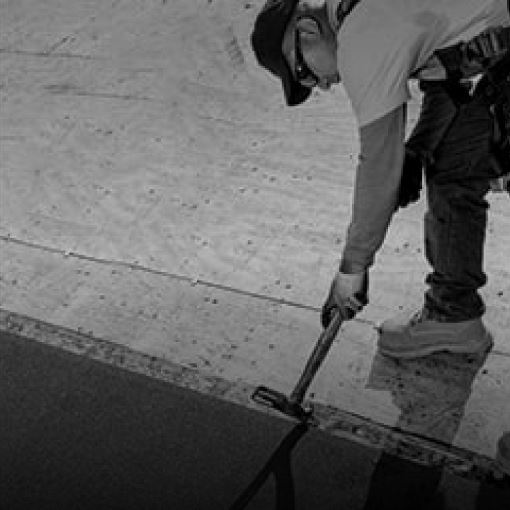 Shaded image of a GAF roofer installing GAF leak barrier on a residential roof