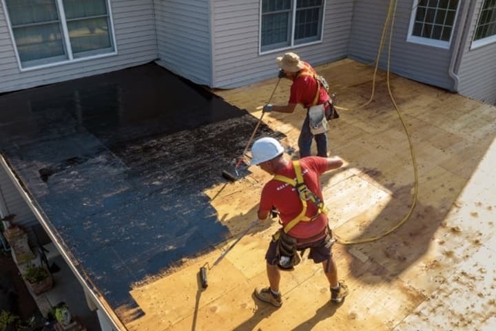 GAF roofing contractors rolling on LIBERTY Asphalt Primer.