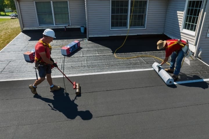 GAF roofing contractors installing LIBERTY SBS Self-Adhering Cap Sheet on a flat roof.