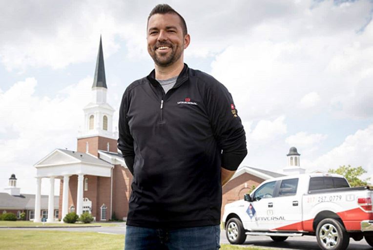 A male GAF academy student stands proudly after becoming a well-trained, qualified GAF roofer.