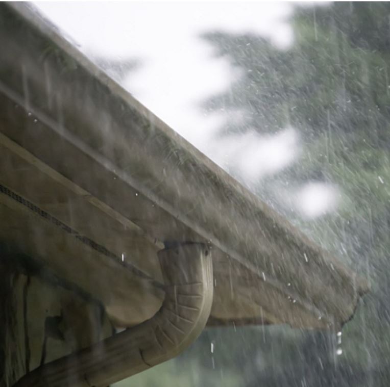 Rain poring with gutter on house in the background