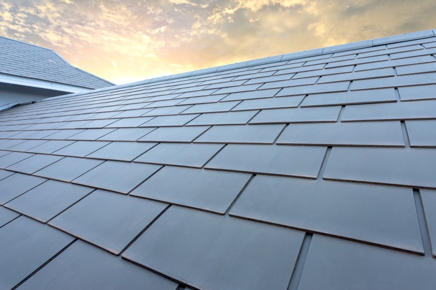 Slate roof against blue sky, Gray tile roof of construction house with blue sky and cloud of the sun