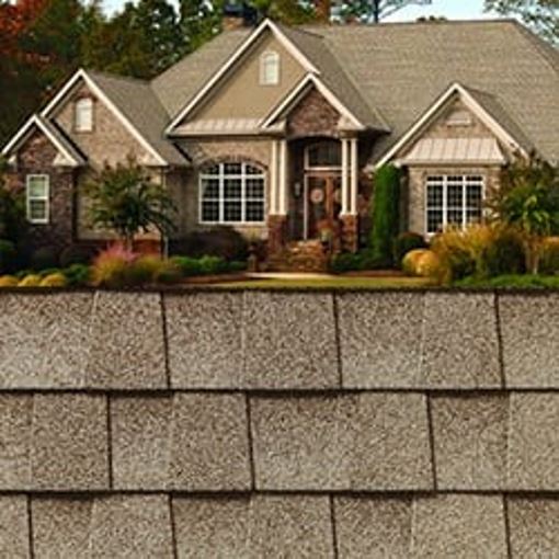 GAF Timberline HDZ golden amber shingle closeup with sample product image on a brick house.