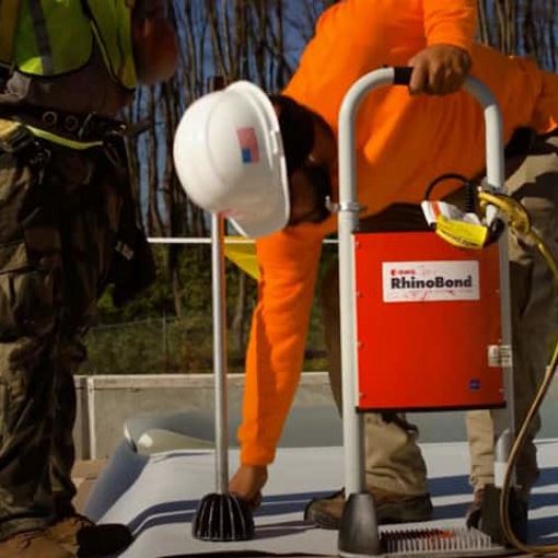 Contractors on commercial roof working on an induction welding roof installation