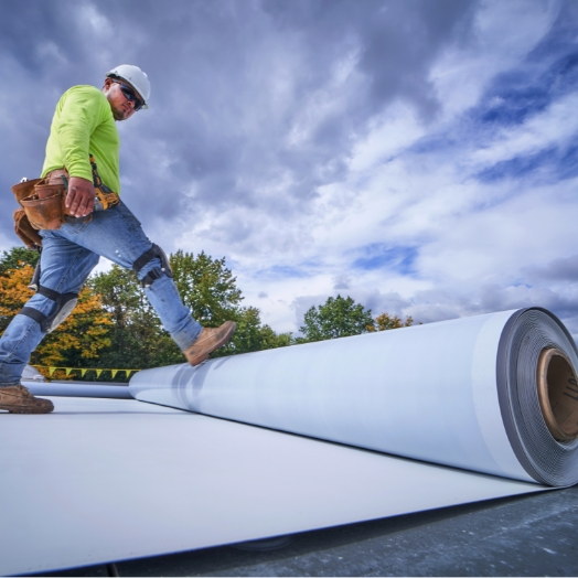 GAF contractor applying TPO roll to flat roof