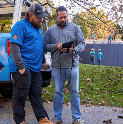 Two men standing outside of a roofing job