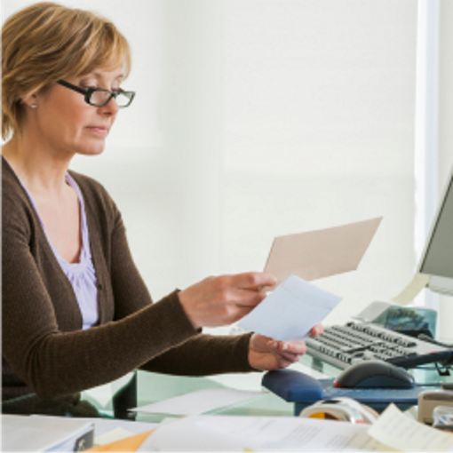 Woman near computer holding envelope